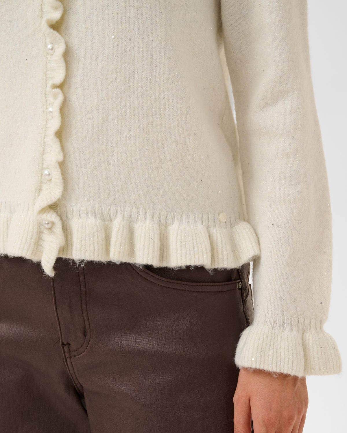 Nærbilde av perleknapper og volang på hvit Cream cardigan